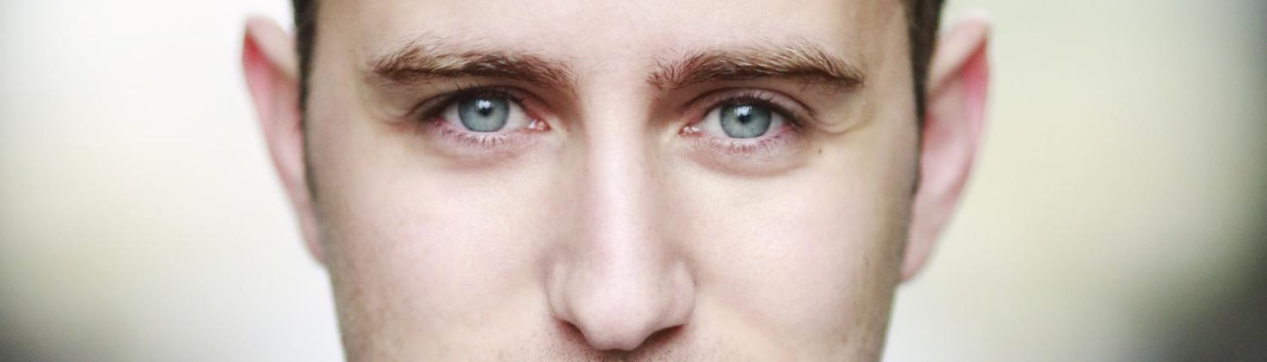 Professional headshot of Guy Woolf, who has blue eyes and wavy brown hair