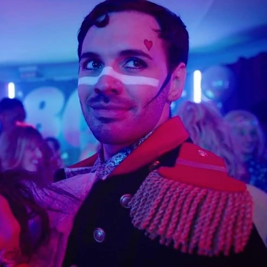 A still from Channel 4’s ’The Windsors’. Mateo Oxley (as Count Edoardo Mapelli-Mozzi) is in fancy-dress as Adam Ant, complete with facepaint and epaulettes. He is looking romantically off into the distance.